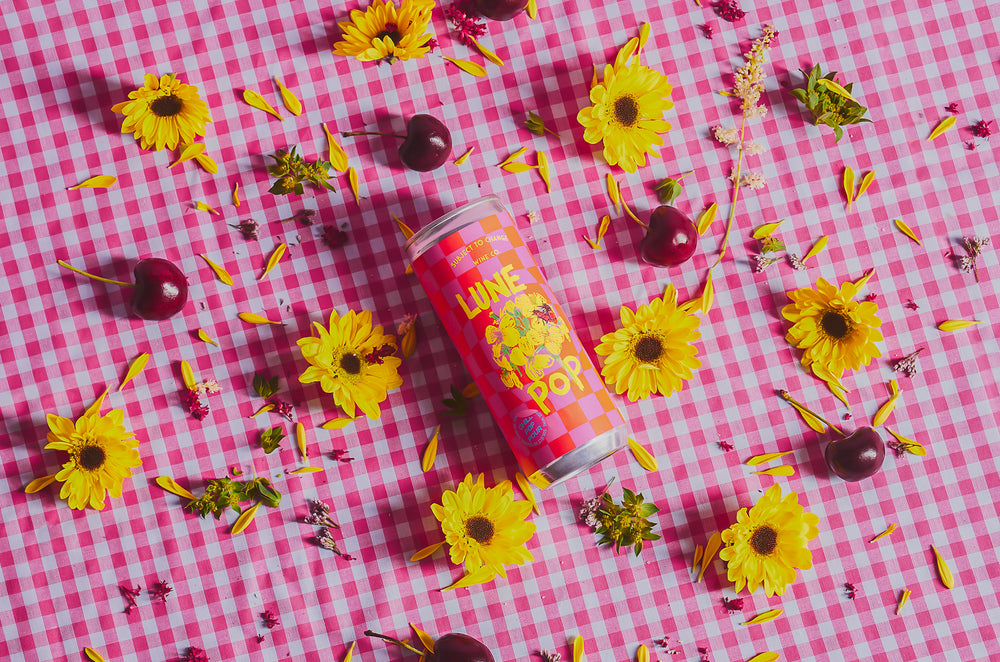 
                  
                    Load image into Gallery viewer, 2021 &amp;#39;Lune Pop&amp;#39; Sparkling Red Can on pink gingham cloth with yellow flowers and cherries
                  
                