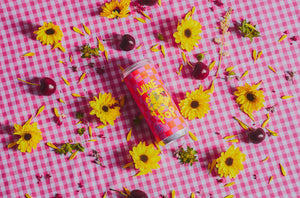 2021 'Lune Pop' Sparkling Red Can on pink gingham cloth with yellow flowers and cherries